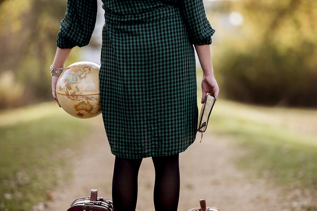 Picture of a woman with a bible in one hand and the globe in the other