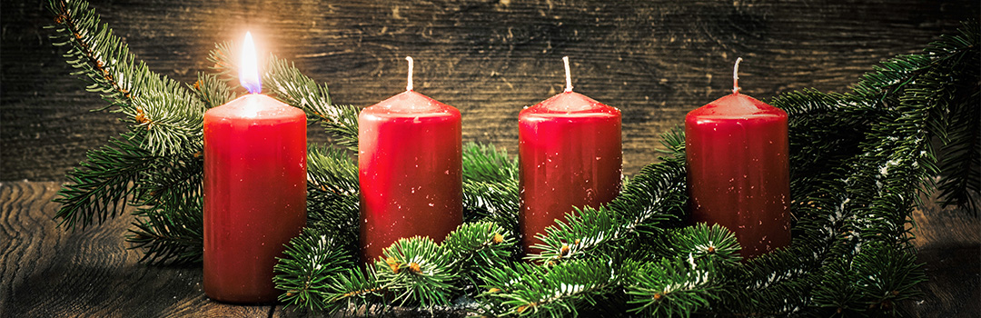 Red advent candles with one lit signifying the first Sunday of Advent